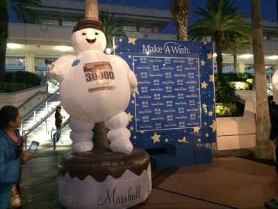 Marshall the Hot Chocolate Race mascot next to the Make A Wish donation station.