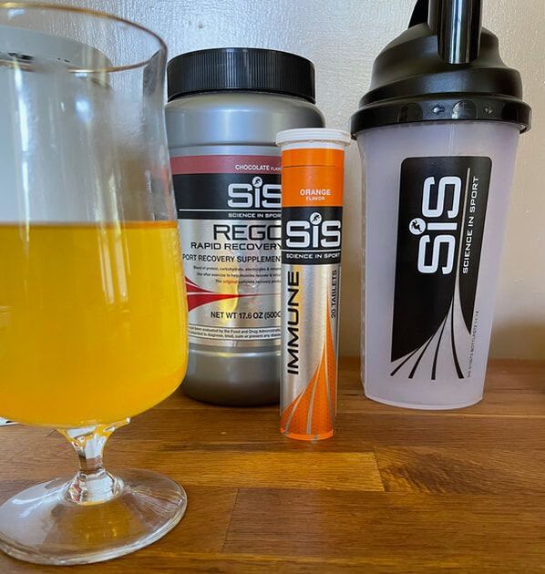 Glass next to SiS Immune tablets. Sis Recovery protein and tumbler in background.