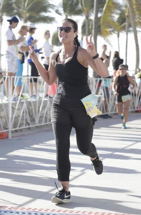 Girl runner crosses the finish line at 305 Half Marathon in Miami Beach, FL.