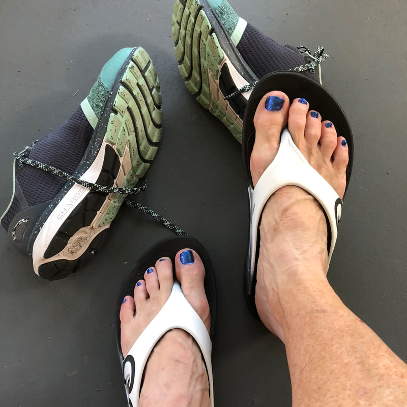 Feet in Oofos sandals.