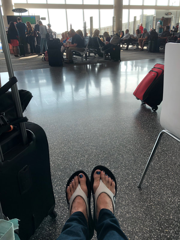 Wearing Oofos sandals in airport.